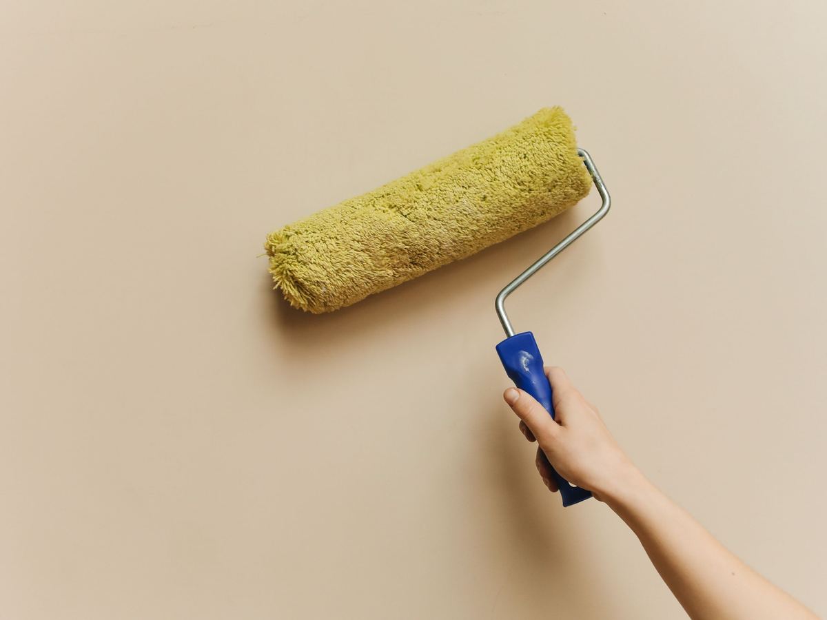 Hand mit Farbroller beim Streichen einer Wand